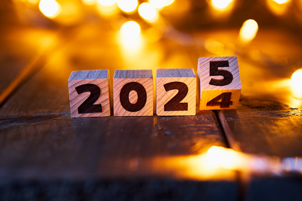 从2024年到2025年的过渡，以质朴表面上的木块为代表，背景中温暖的散焦仙女灯照亮，营造出舒适的除夕氛围。图片下载