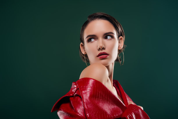 照片中迷人的女孩穿着红色的时尚大衣，感觉诱人的样子侧面孤立的深色背景图片下载