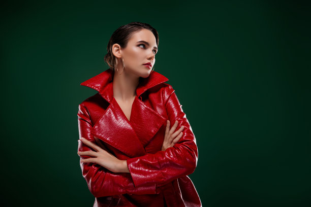 照片中冷静的女士双手交叉穿着时尚的外套，看起来空间空旷孤立的绿色背景图片下载