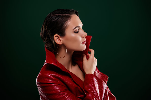 侧面照片迷人的女士闭上眼睛触摸红色大衣享受孤立的深色背景图片下载