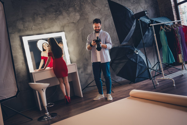 时尚摄影师工作与年轻的模特妇女准备照片会议化妆在现代工作室室内图片下载