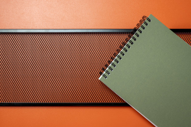 一个绿色的螺旋笔记本放在黑色的金属框架上图片下载