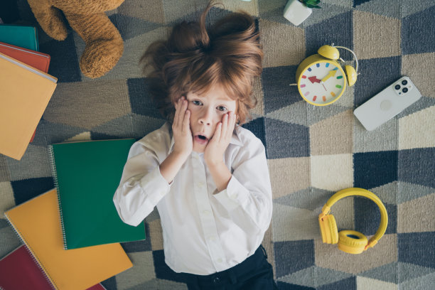 照片中迷人的兴奋的好有趣的小男孩躺在地板地毯手脸哇学校用品出售室内图片下载