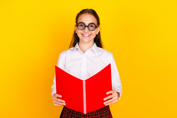 照片肖像迷人的十几岁的学生女孩读书穿时髦的制服孤立的黄色背景图片下载