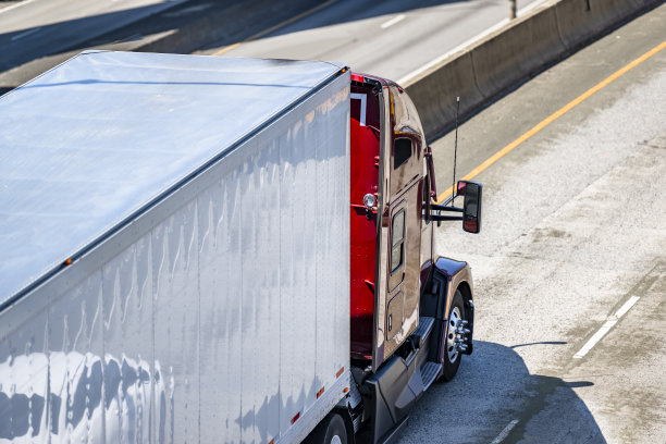 高驾驶室红色大钻机长途半挂车，以干式货车半挂车运输货物，行驶在分隔的高速公路上图片下载