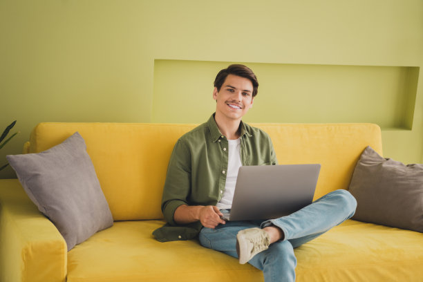 照片英俊迷人的男人穿着时尚的衣服坐在柔软的沙发家里的房子里图片下载