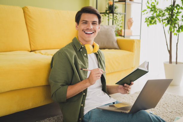 年轻人坐在地毯上使用现代设备上网本在家工作的照片图片下载