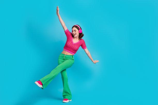 满意的漂亮可爱的女人的全尺寸照片，波浪发型，穿着粉红色的顶部舞蹈，在蓝色的背景下享受乐趣图片下载