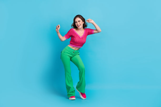 漂亮甜美的女人的全尺寸照片，波浪发型，穿着粉红色的顶部跳舞，看起来空白的空间孤立在蓝色的背景图片下载