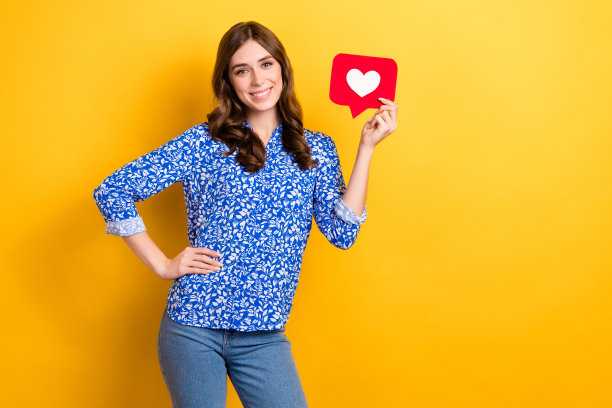 照片中华丽积极的女博主穿着时尚的衣服，拿着红色的纸卡，站在黄色背景上的空白空间图片下载