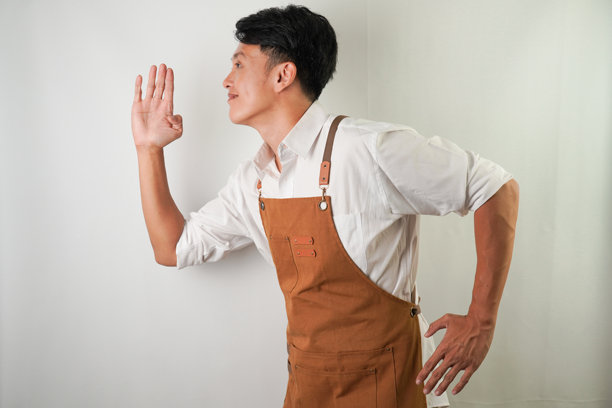 兴奋的年轻亚洲人穿着卷起的白袖衬衫和棕色围裙与跑步姿势。侧视图-隔离在白色背景上。图片下载