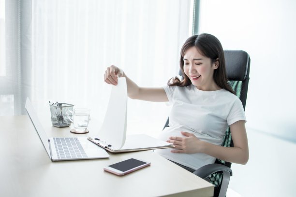 怀孕的女商人在办公室用笔记本电脑工作图片下载