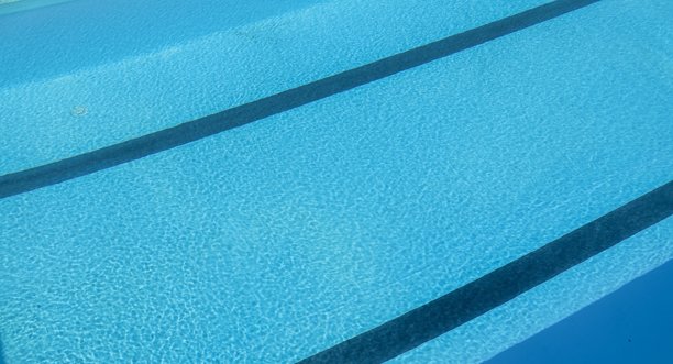 游泳池有蓝色的水和阳光反射。游泳池背景图片下载