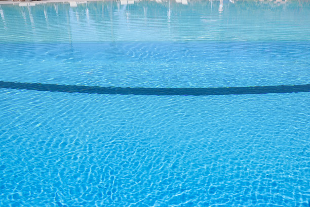 游泳池有蓝色的水和阳光反射。游泳池背景图片下载