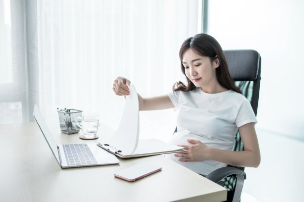 怀孕的女商人在办公室用笔记本电脑工作图片下载