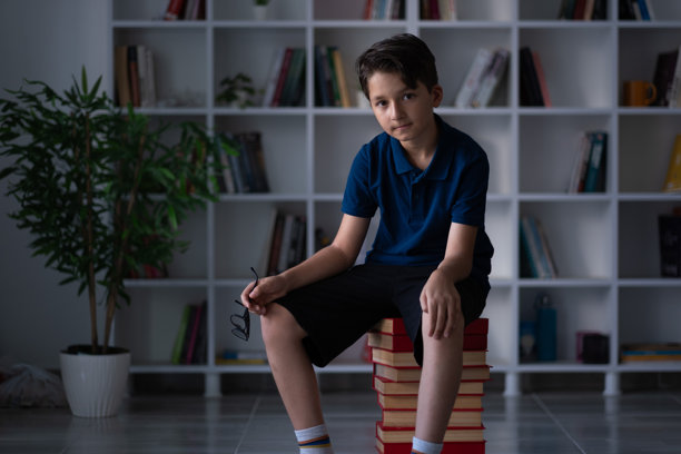 小男孩坐在一摞书上图片下载