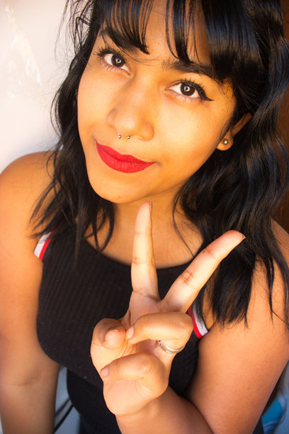 一名年轻女子的特写照片，她正在做和平手势图片下载