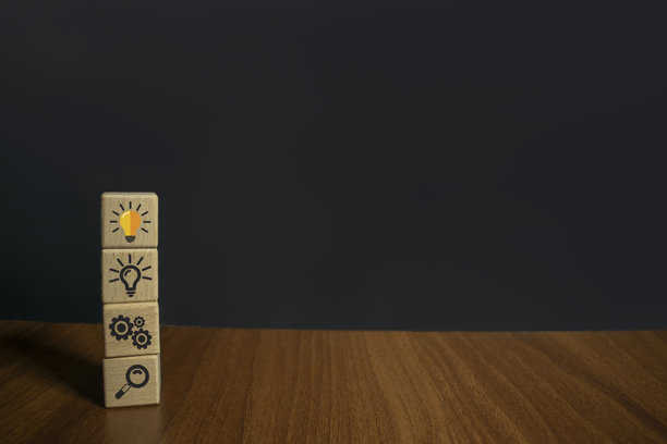 企业战略和行动计划的概念、想法和创新。精心挑选的木质立方体块堆叠符号，问题和灯泡图标在木桌和黑色背景。图片下载