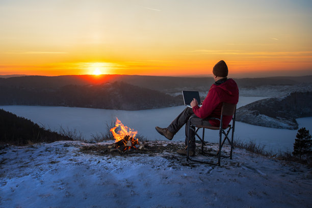 马在冬季野外露营时使用笔记本电脑。图片下载