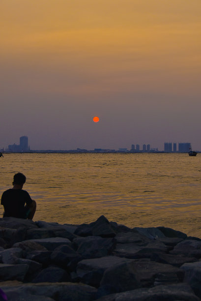 一名身份不明的男子在安科尔海滩放松和享受日落的剪影照片。图片下载