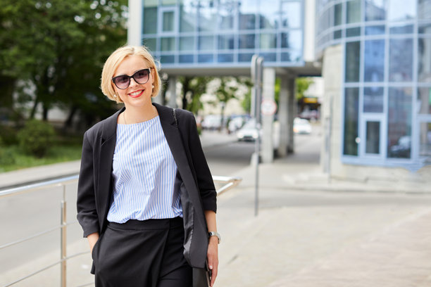 漂亮的金发女郎穿着西装走在街上。一个穿着商务装的女人在城市里走来走去图片下载