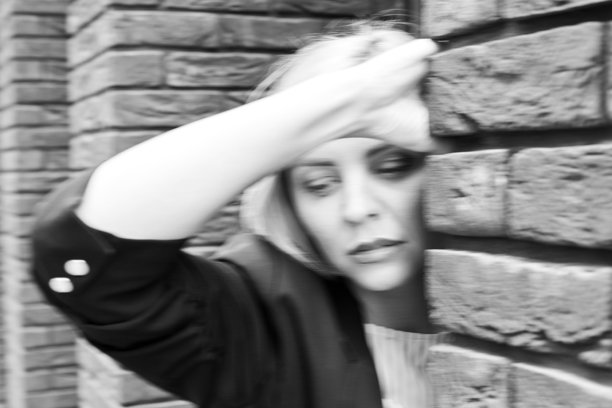 金发碧眼的年轻女子站在一个白色的外墙与复制空间在城市街道看着相机图片下载