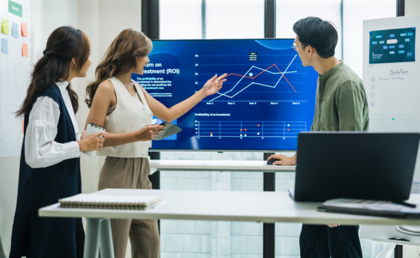 一位亚洲女性领导人在现代化的办公室里展示财务数据和战略，大屏幕上显示着图表和图表图片下载