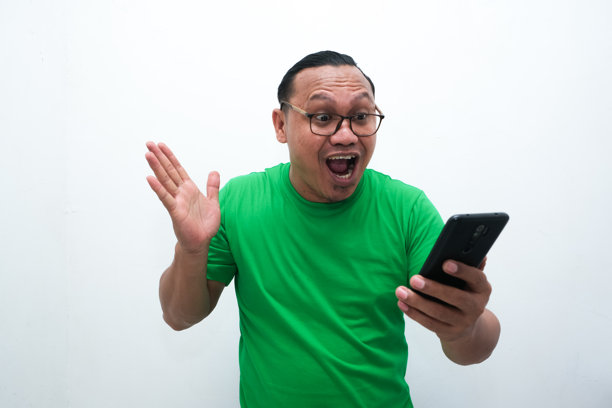 照片中，一名亚洲男子看着手中的手机，露出震惊的表情图片下载