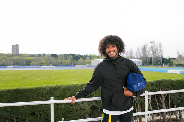 一个带着蓝色包的非洲人站在体育中心图片下载
