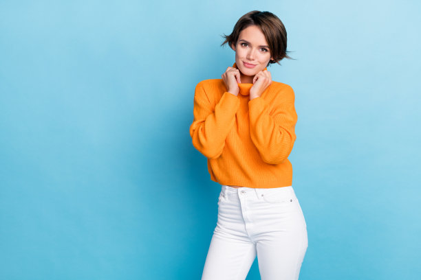 照片肖像迷人的年轻女子触摸衣领享受秋季购物穿着时尚的橙色看起来孤立的蓝色背景图片下载