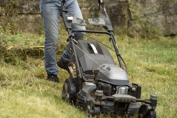 一个人在用黑色割草机割草图片下载