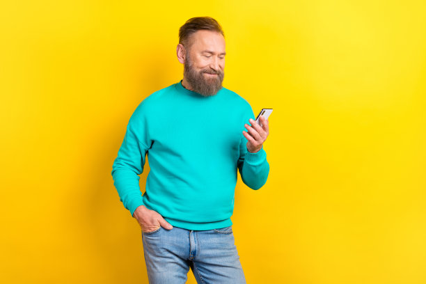 成功打扮的绅士穿着时髦的青色服装的照片，使用设备速度4g连接孤立在黄色背景上图片下载