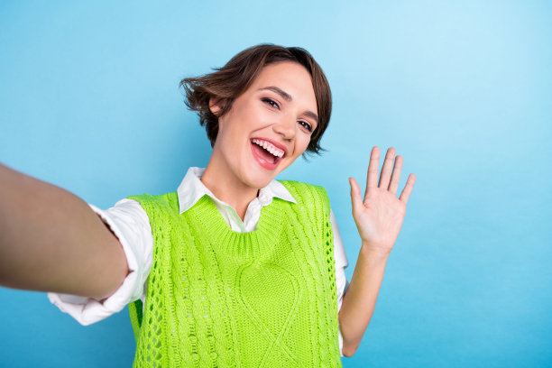 照片中，开朗可爱的女博主穿着绿色时尚的衣服和粉丝聊天，在青色的背景下，空无一物图片下载