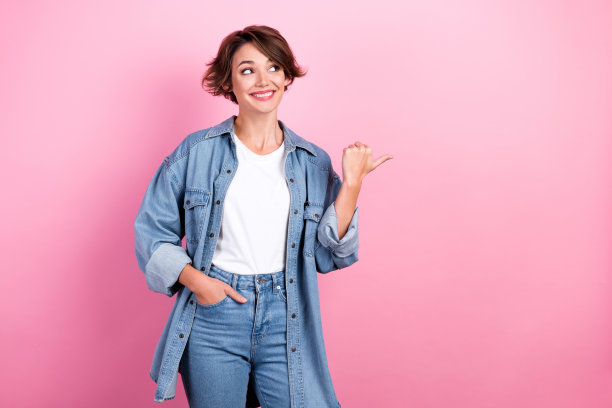 照片的年轻开朗的积极的广告穿着时尚的模特鲍勃棕色的头发直接手指出口衣服孤立在粉红色的背景图片下载