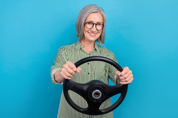 照片中老年成熟年龄白发正装制服女士驾驶新车主方向盘正常速度孤立在蓝色背景图片下载