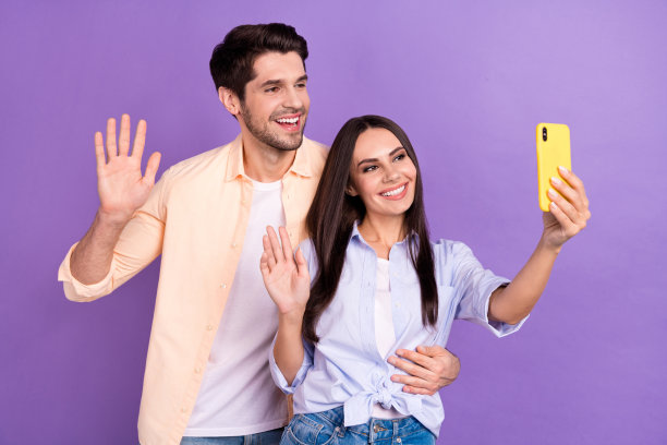 照片记录视频年轻夫妇学生情侣握手问候订户分享转发频道持有手机孤立在紫色背景图片下载