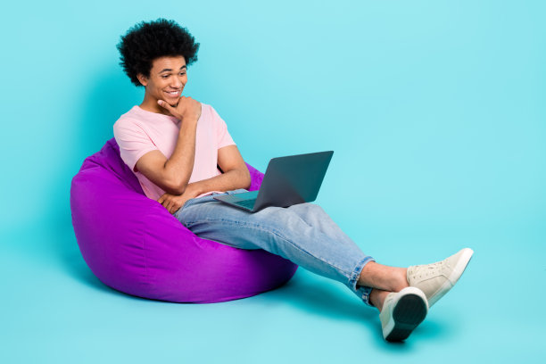 年轻人的全身尺寸照片头发雪佛兰聪明的学生坐着，看它的头脑发展导师孤立的青色背景图片下载