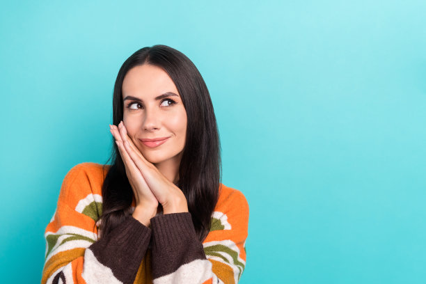 照片中，梦幻甜美的女人穿着条纹毛衣，手臂和脸颊看起来空白，孤立的绿松石色背景图片下载