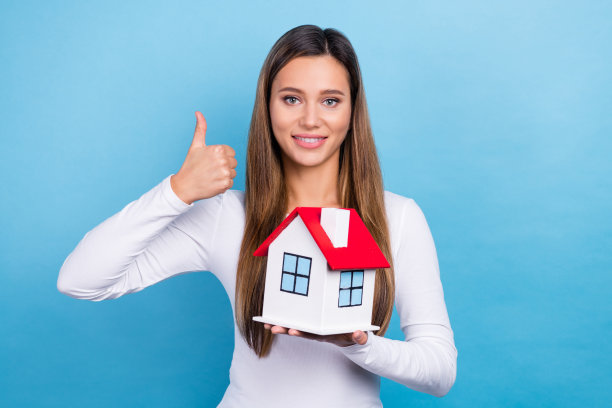 照片可爱的令人惊叹的满意的女士穿着时尚的衣服，拿着房子大拇指，漂亮的购买孤立的蓝色背景图片下载