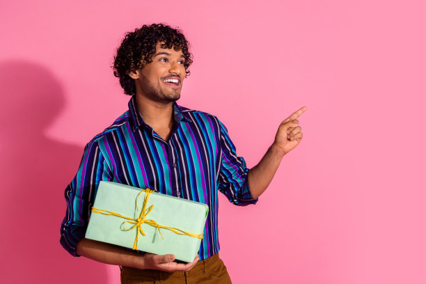 漂亮的年轻人的照片礼盒点手指空的空间穿衬衫孤立的粉红色背景图片下载