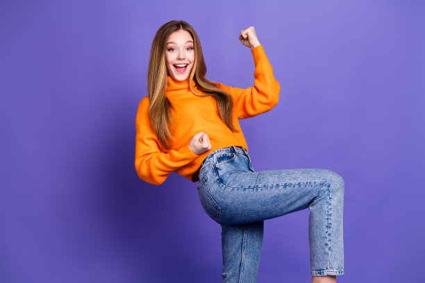 青春的肖像照片迷人的金发可爱的快乐的微笑女孩胜利的呼喊举起拳头孤立在紫罗兰色的背景图片下载