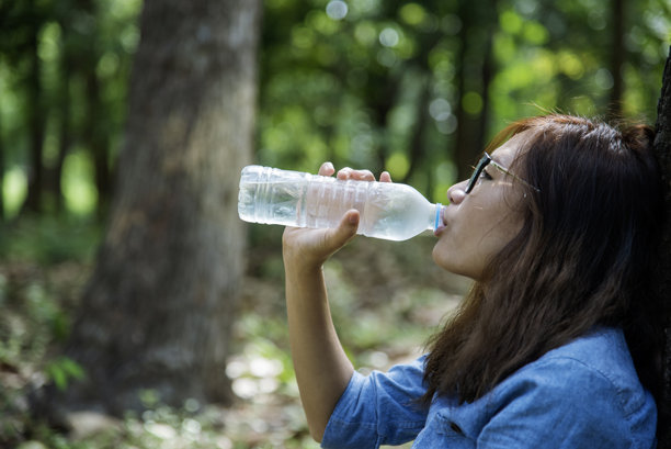 年轻女子喝水壶户外公园游客。亚洲女性饮用水瓶健康人快乐微笑。幸福美丽的亚洲中国女性拿着矿泉水瓶的生活方式图片下载