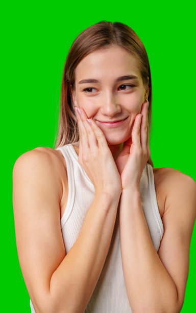 一头棕色长发的年轻女子对着绿幕害羞地微笑图片下载