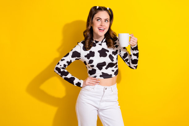 照片正面的女孩在黑色斑点服装看起来空旷的空间喝天然新鲜可口的奶茶孤立亮色背景图片下载