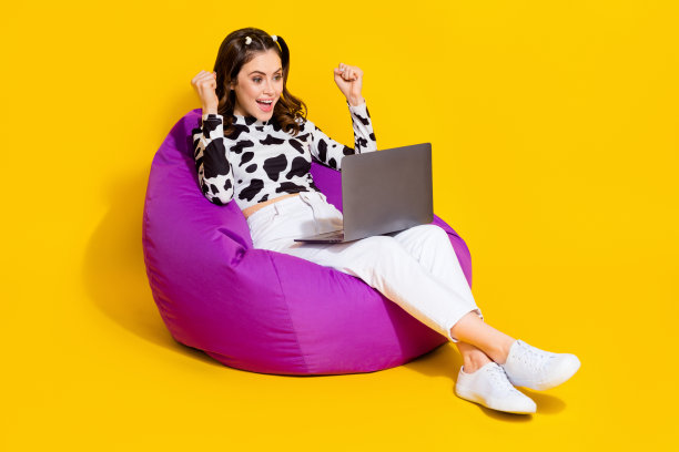照片时髦的幸运女士穿着牛皮衬衫坐在豆袋上升拳头小玩意空空间孤立的黄色背景图片下载
