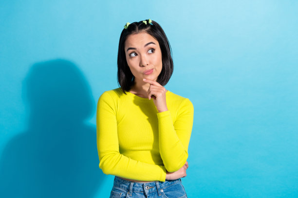 年轻有趣有吸引力的韩国女士的照片触摸下巴，思考她未来的商业品牌理念，在蓝色背景上看起来孤立的模型图片下载