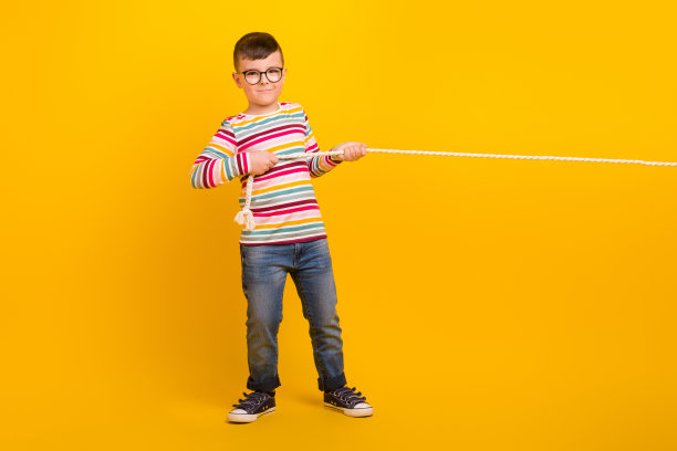 学生的全身照片有休息时间与朋友玩拔河游戏孤立在鲜艳的色彩背景图片下载