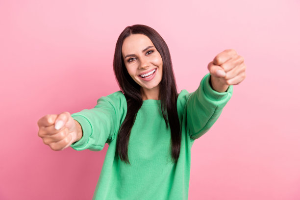 照片好心情漂亮的女人直发穿着绿色运动衫抱着想象的方向盘孤立在粉红色的背景图片下载