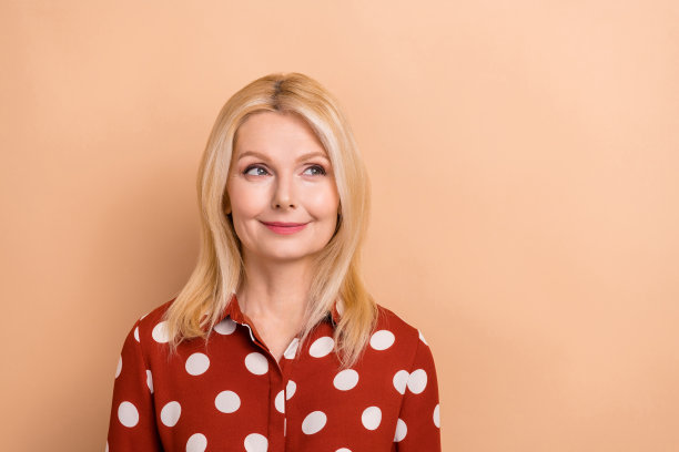 照片中有魅力的中年商务女士穿着正装衬衫，看起来空空荡荡的空间广告销售购物孤立的米色背景图片下载