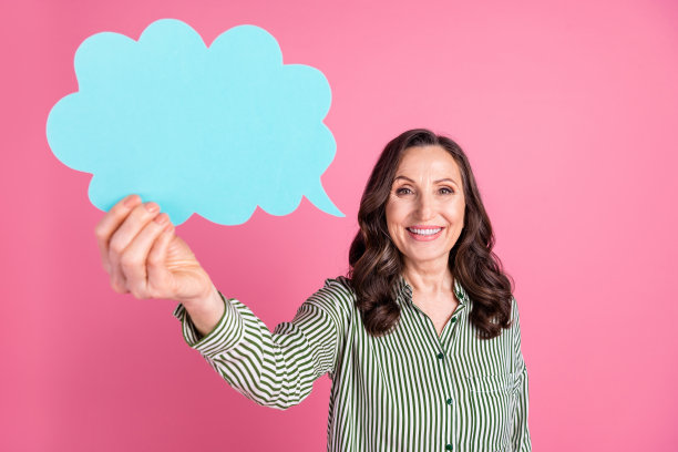 照片中漂亮的老年妇女手持空的空间泡泡卡，穿着条纹衬衫孤立在粉红色的背景上图片下载